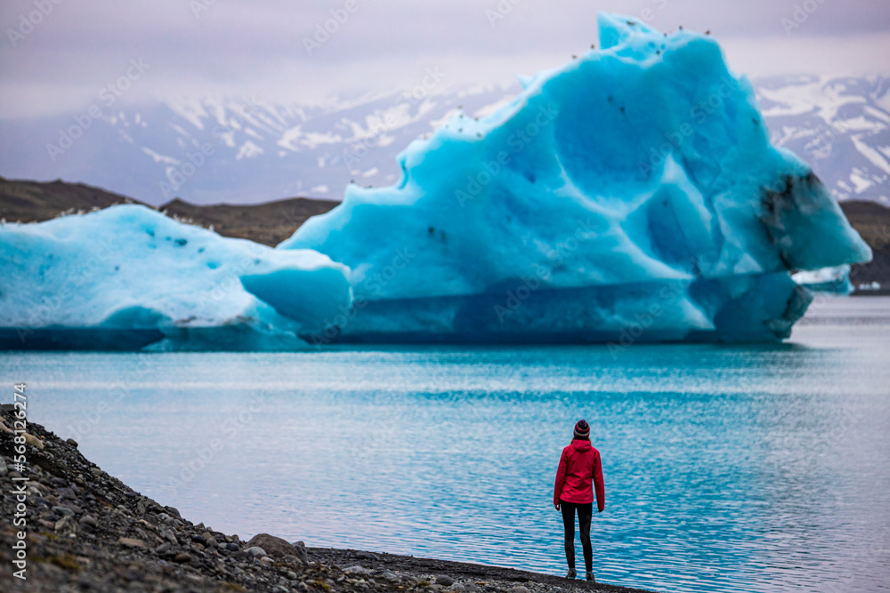 A girl wearing an Icelandic wool cap admires the unique blue icebergs on Lake Jökulsárlón, a unique glacial lake at the Vatnajökull glacier