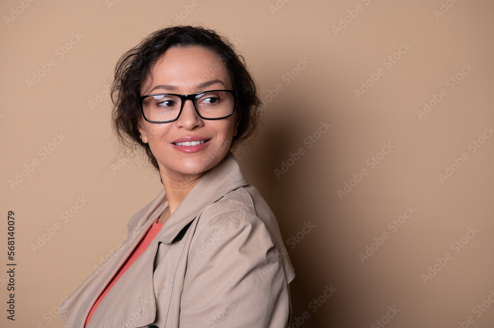 Close-up portrait. Attractive middle-aged woman, wearing stylish eyeglasses, smiling on beige background. Ophthalmology