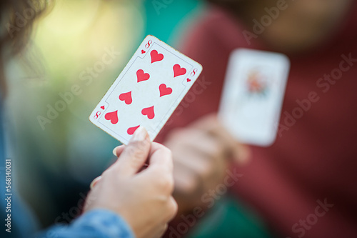 Card playing in a spring garden: Couple are sitting on a table, relaxing and playing cards together. Blurry background.
