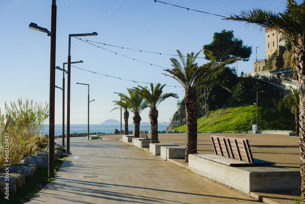 A deserted alley next to the sea, with palm trees, benches and lanterns in Europe