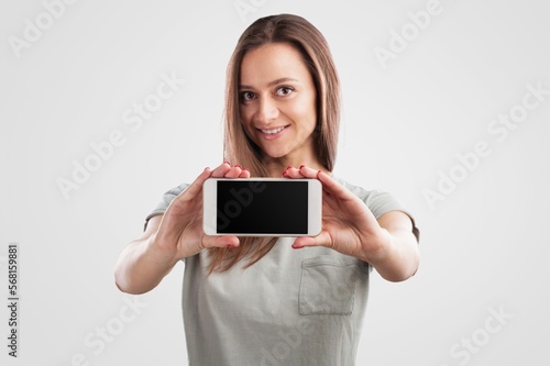 Happy young woman hold a phone and posing