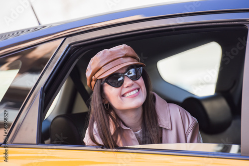 happy smiling girl discovering Barcelona through the window of the cab, stylish woman with a cap and sunglasses