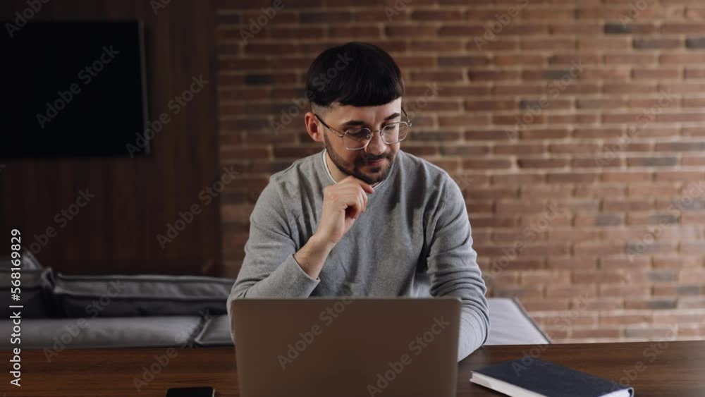 Smiling Caucasian Man Working on Laptop Computer while Sitting on a Sofa Couch in Stylish Cozy Living Room. Happy guy Having Fun at Home. Browsing Internet, Smiling Caucasian Man Working on Laptop Computer while Sitting on a Sofa Couch in Stylish Cozy Living Room. Happy guy Having Fun at Home. Browsing Internet,