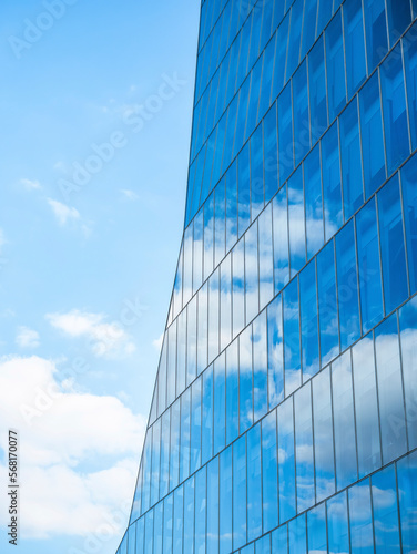 the sky with white clouds reflecting in the glass windows of a modern office building.