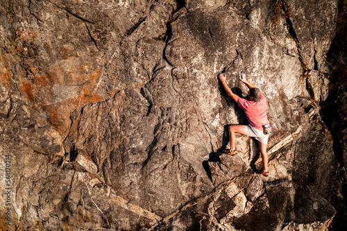 Male rock climber over the ocean, free solo, no rope, adventure sport, rock face, cliff.