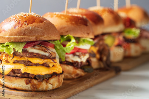 Many different burgers with ingredients on a wood plate. High quality photo