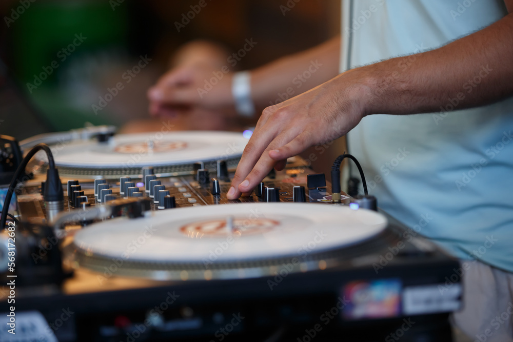 Club DJ scratching vinyl records with sound mixer and turntables. Professional disc jockey plays set on party