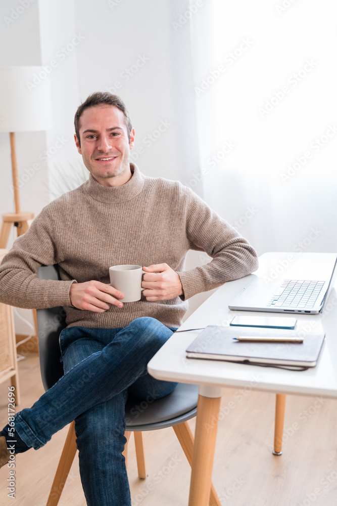 Cheerful man with coffee and laptop at home