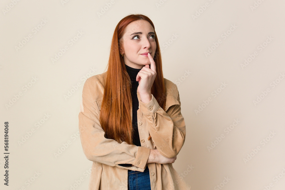 Young red hair woman isolated looking sideways with doubtful and skeptical expression. Young red hair woman isolated looking sideways with doubtful and skeptical expression.