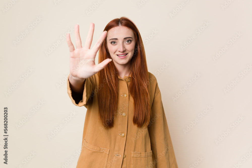 Young red hair woman isolated smiling cheerful showing number five with fingers. Young red hair woman isolated smiling cheerful showing number five with fingers.