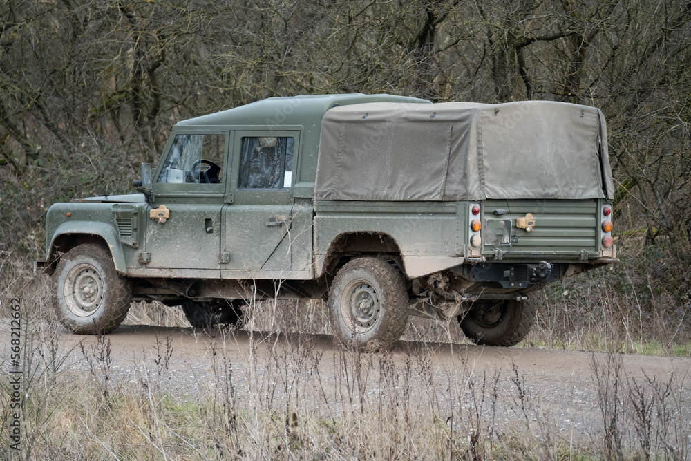British army Land Rover Defender Wolf LWB medium size utility vehicle driving along a mud track, military exercise Wilts UK