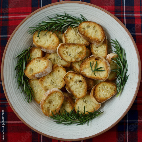 ceramic bowl with sliced toasted rounds of ciabatta bread and sprigs of fresh rosemary