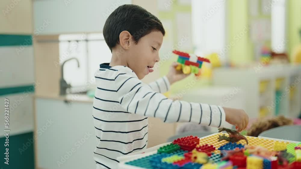 Adorable hispanic boy playing with construction blocks sitting on table at kindergarten Adorable hispanic boy playing with construction blocks sitting on table at kindergarten