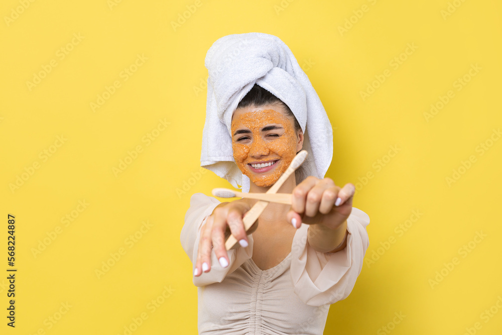 A cute young girl with a scrub mask on her face brushes her teeth against a yellow background. A cute young girl with a scrub mask on her face brushes her teeth against a yellow background.