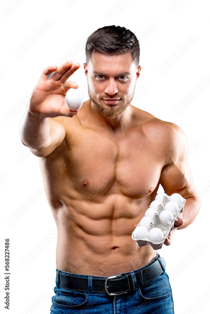Handsome young sportsman is holding a packaging with eggs, healthy food protein, gray background. showing one egg to camera. Naked torso, healthy life concept. Handsome young sportsman is holding a packaging with eggs, healthy food protein, gray background. showing one egg to camera. Naked torso, healthy life concept.