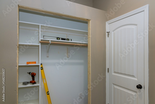 Installation of an interior white melamine shelf to be used to store clothing, with many empty shelves accommodate clothing photo