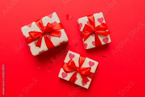 Top view photo of valentine day decorations gift box with red ribbon bow on colored background. Holiday gift boxes with top view © sosiukin