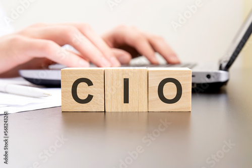 cio - acronym from wooden blocks with letters. background hands on a laptop with blur. business concept.