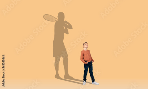 Little redhead boy and shadow of adult tennis player behind