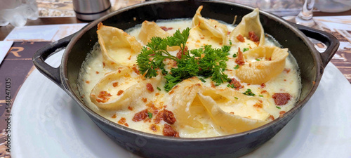 Baked conchiglioni pasta shells stuffed with brie cheese, four cheese salce and parma ham crispy with parmesan gratin. photo
