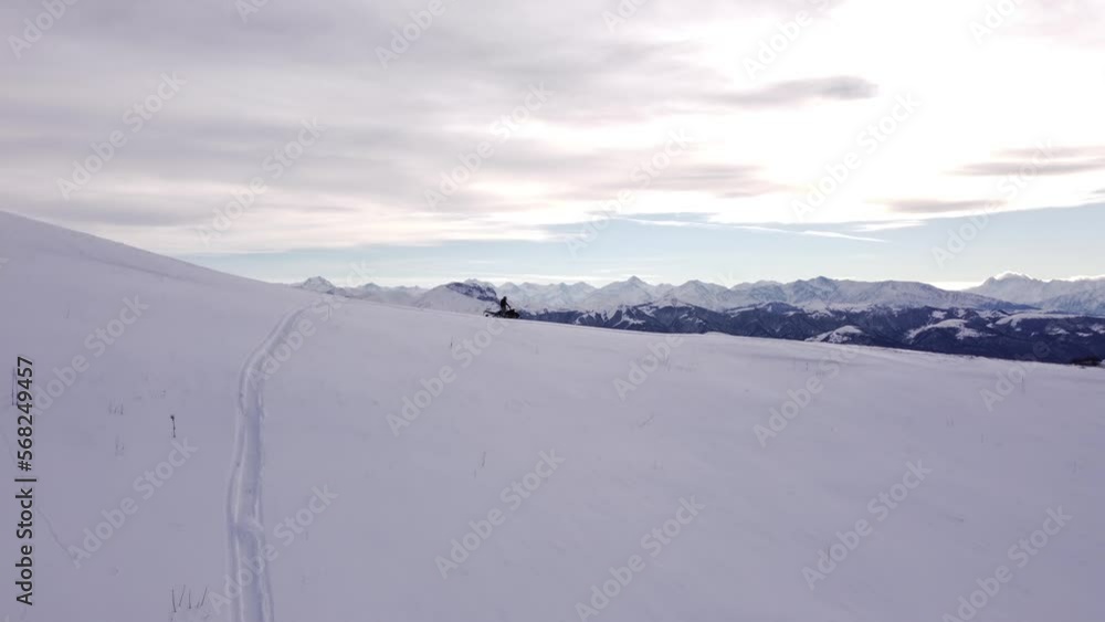 A man on a snowmobile roams the mountains 2023 filming from a drone A man on a snowmobile roams the mountains 2023 filming from a drone