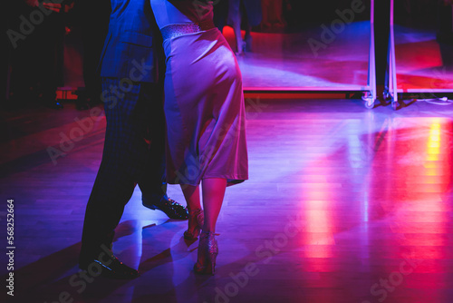 Couples dancing traditional latin argentinian dance milonga in the ballroom on a festival, tango studio, salsa, bachata and kizomba lesson in the red and purple lights, rehearsal in the dance class