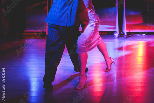 Couples dancing traditional latin argentinian dance milonga in the ballroom on a festival, tango studio, salsa, bachata and kizomba lesson in the red and purple lights, rehearsal in the dance class