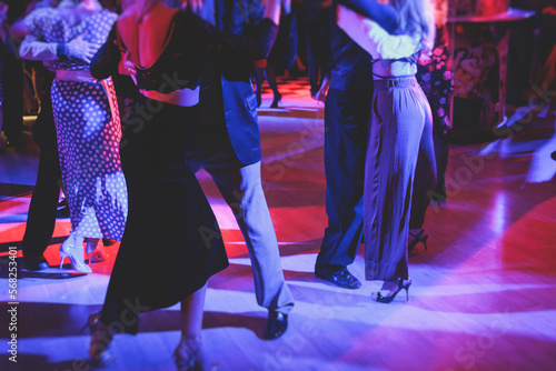 Couples dancing traditional latin argentinian dance milonga in the ballroom on a festival, tango studio, salsa, bachata and kizomba lesson in the red and purple lights, rehearsal in the dance class photo