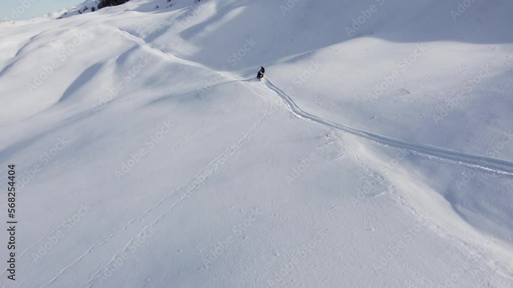 A man on a snowmobile roams the mountains 2023 filming from a drone A man on a snowmobile roams the mountains 2023 filming from a drone