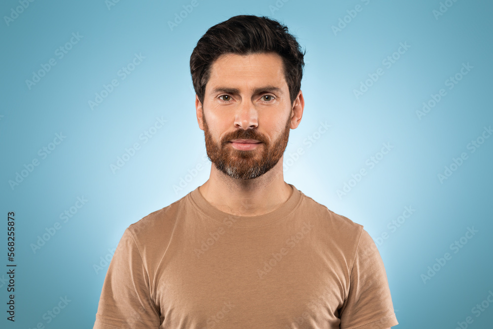 Portrait of handsome middle aged man posing at camera over blue studio background, wearing t-shirt, free space Portrait of handsome middle aged man posing at camera over blue studio background, wearing t-shirt, free space
