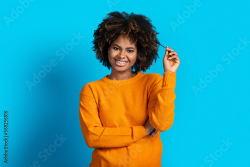 Playful young black woman posing on blue studio background