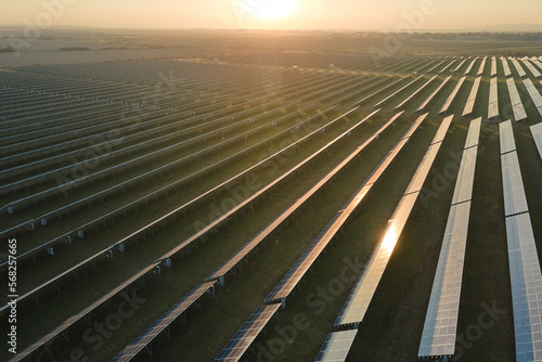 Aerial view of big sustainable electric power plant with many rows of solar photovoltaic panels for producing clean electrical energy at sunset. Renewable electricity with zero emission concept