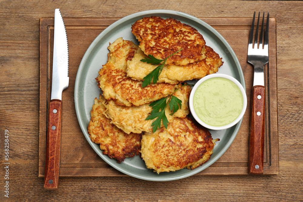 Tasty parsnip cutlets with parsley and sauce served on wooden table, top view Tasty parsnip cutlets with parsley and sauce served on wooden table, top view