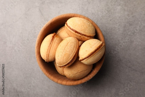 Delicious nut shaped cookies with boiled condensed milk in wooden bowl on gray textured table, top view