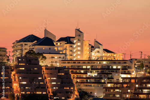 Orange sunset glow over lights in modern hillside apartments