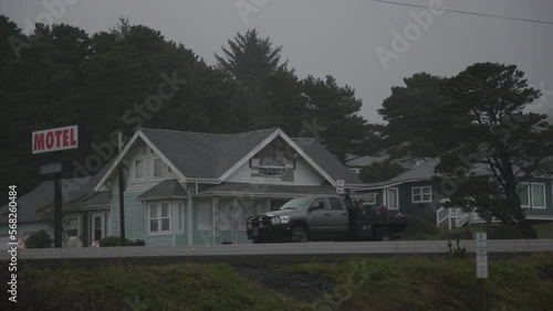 Side view of a passenger car driving along the road with a motel building on side. Traditional American architecture with cloudy skyline above. High quality 4k footage