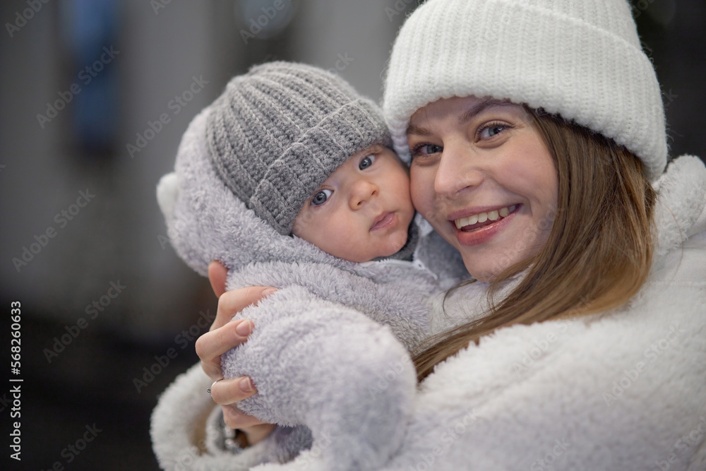 young woman with a baby in her arms walking around the city. mom and son are walking in cold weather, dressed in trendy warm clothes. Mom gently hugs her child. young woman with a baby in her arms walking around the city. mom and son are walking in cold weather, dressed in trendy warm clothes. Mom gently hugs her child.