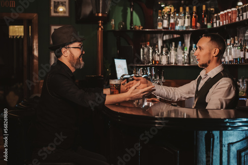 man communicates with a bartender at bar with beer in a pub