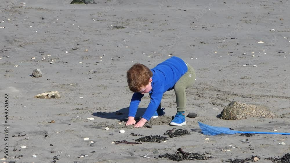 Red headed boy playing with Bucket spade on a sandy beach Red headed boy playing with Bucket spade on a sandy beach