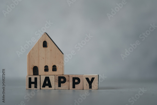Wooden blocks with the text words HAPPY with a model wood home model. The concept of housing a young family, happy in home. Happy family together.