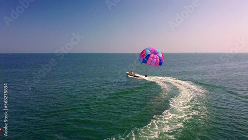 aerial drone shot of boat pulling parachute over the sea in lignano parasailing photo