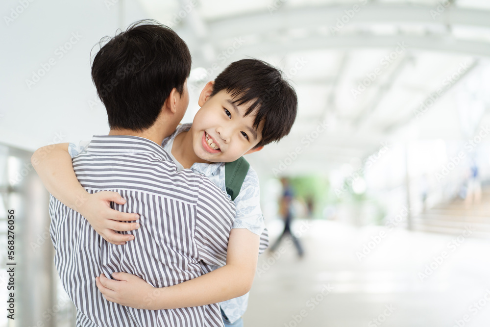 Happy cheerful Asian little boy running to his father at the railway or sky train station after his father returned from the traveling trip. Happy Asian family father and son concept. Happy cheerful Asian little boy running to his father at the railway or sky train station after his father returned from the traveling trip. Happy Asian family father and son concept.