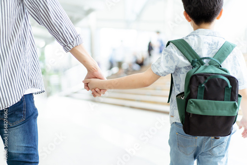 Asian man holding on his little son's hand while traveling in the city.