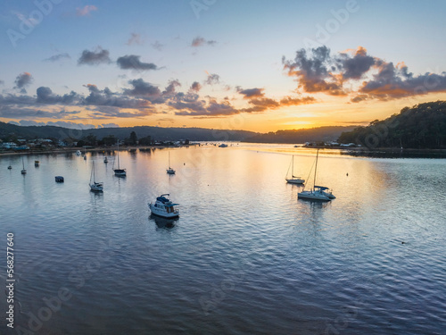 Aerial sunrise waterscape with boats and scattered clouds © Merrillie