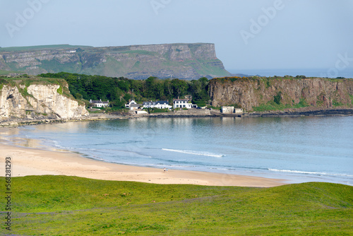 White Park Bay on the north Antrim coast, Northern Ireland. The basalt cliffs of the Giants Causeway rise behind the fishing village of Portbradden photo
