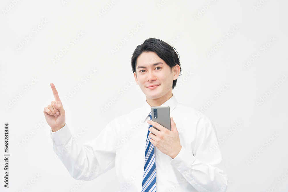 スマホを持って左を指差すビジネスマン 白背景 スマホを持って左を指差すビジネスマン 白背景