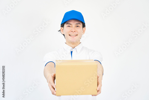 荷物を差し出すポロシャツとキャップのユニフォームの男性　（引越し業者・運送業・宅配業者） © siro46