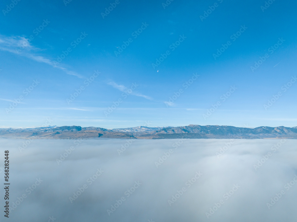 Obraz premium dense fog covering foothills of northern Colorado with clear mountains at a horizon, aerial view of winter morning