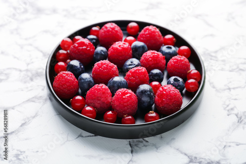 Plate of fresh berries on light background