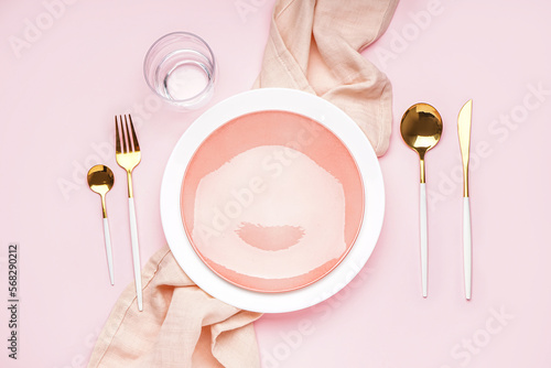 Table setting with golden cutlery on pink background